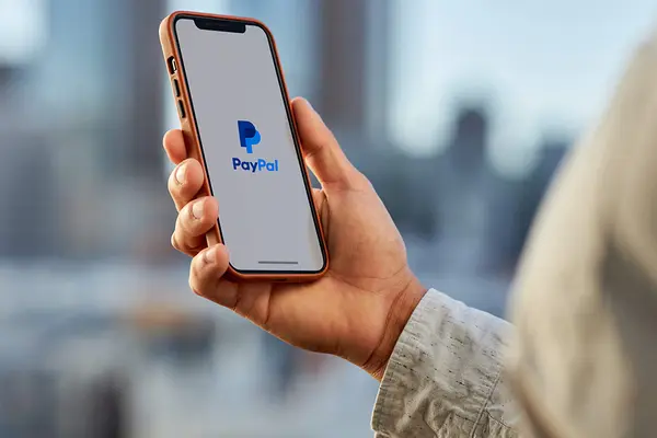 Hand hält Smartphone mit dem Logo von PayPal