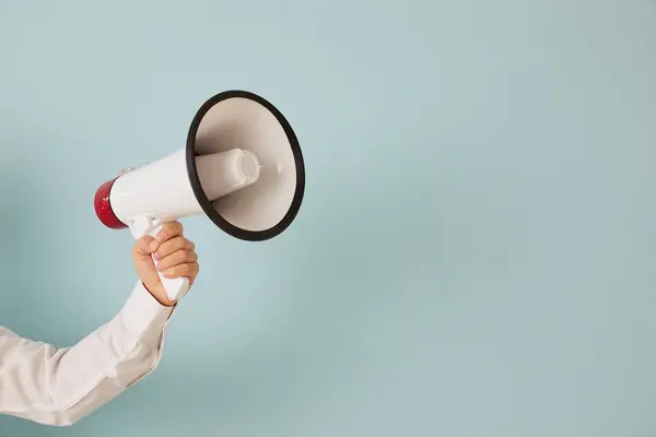 Ein Arm hält ein Megaphone ins Bild. 