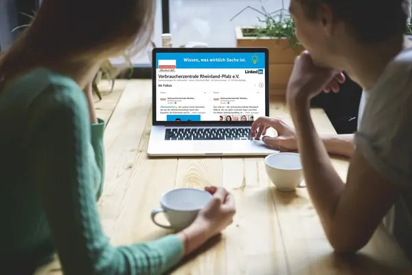 zwei Frauen sitzen vor einem PC auf dem LinkedIn geöffnet ist.