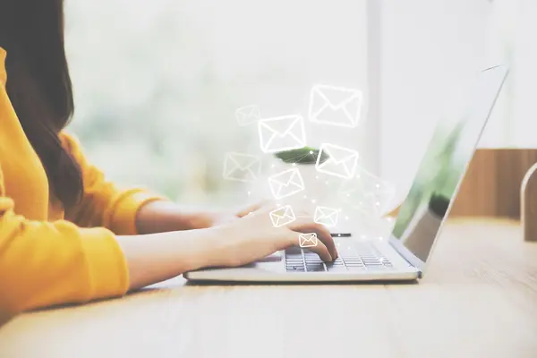 Frau an Laptop, die Mails schreibt.