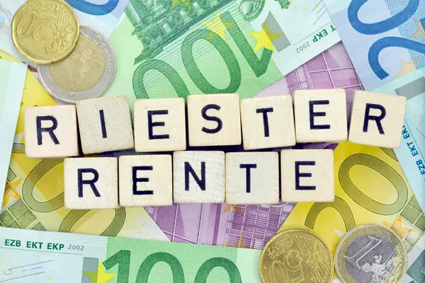 Scrabble-Steine, die das Wort Riester-Rente bilden, liegen auf Geldscheinen und Münzgeld