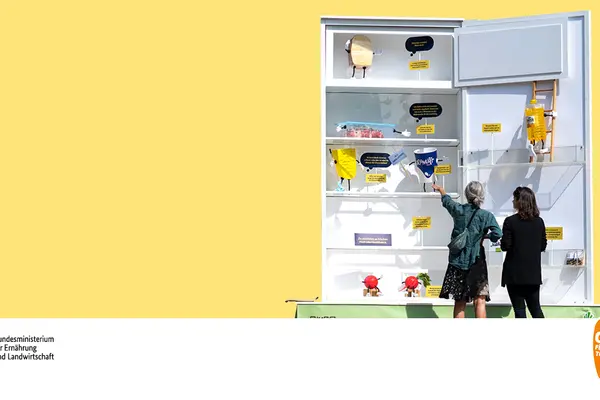 Zwei Frauen stehen vor einem überdimensionalen Kühlschrank.