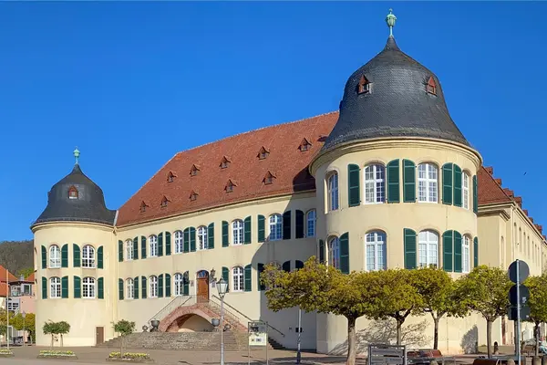 Ein altes Gebäude mit rechts und links jeweils einem breiten Turm. Im Hintergrund ist ein blauer Himmel zu sehen. 
