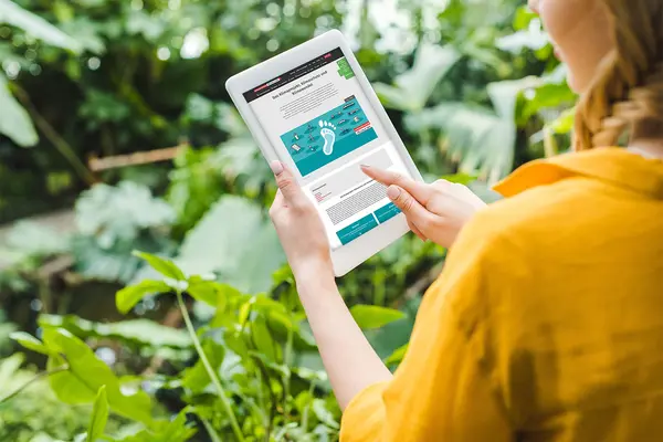 Frau mit Tablet im Grünen.