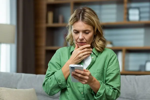 Frau schaut bestürzt auf ihr Smartphone.