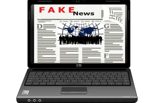 Auf dem Bildschirm eines aufgeklappten Laptops ist das Wort Fake News zu lesen