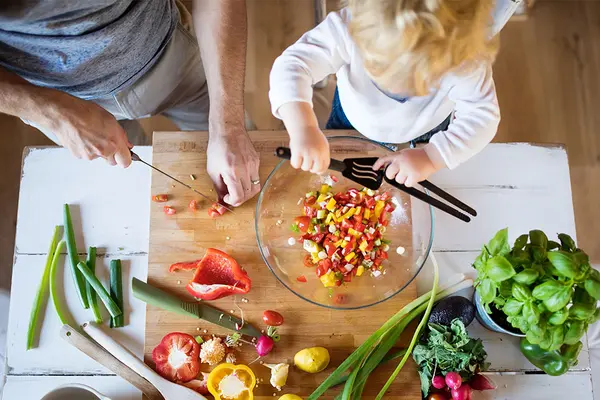 Vater und Kind schneiden gemeinsam Gemüse