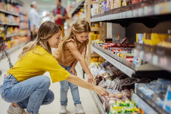 Frau mit Kind am Supermarktregal