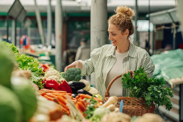 Frau an einem Marktstand mit Obst und Gemüse