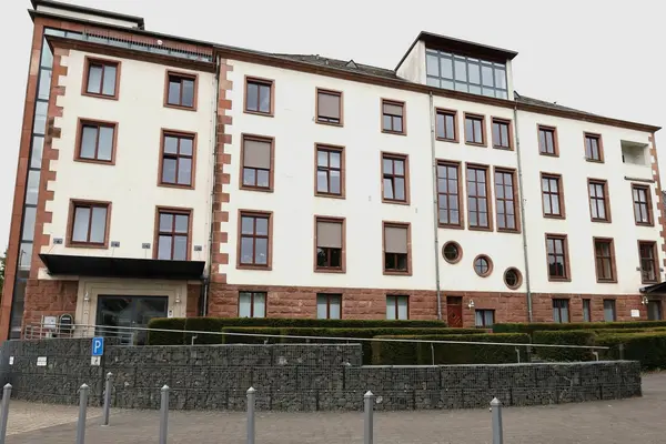 Verwaltungsgebäude mit vielen Fenstern vor bedecktem Himmel