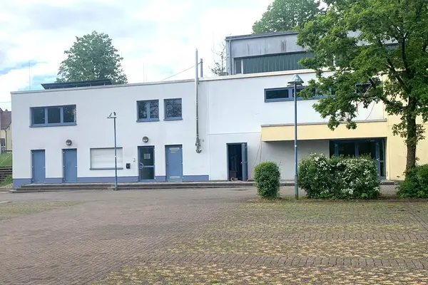 zweistöckiges Gebäude mit weißem Anstrich und blauen Türen