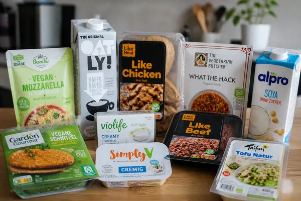 Verschiedene vegane Ersatzprodukte wie pflanzliche Milch, Fleisch- und Käsealternativen stehen auf einer Küchenfläche.