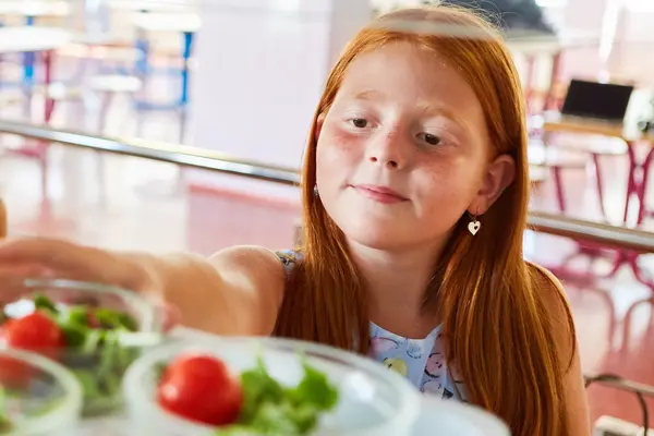 Ein Schulmädchen blickt in die Auslage der Schulkantine