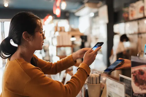 Frau bezahlt an der Theke mit ihrem Smartphone