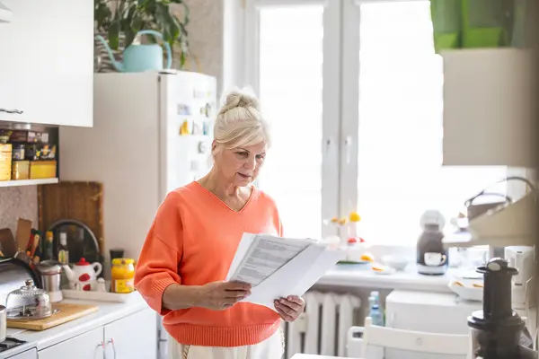 Frau öffnet Rechnung in der Küche