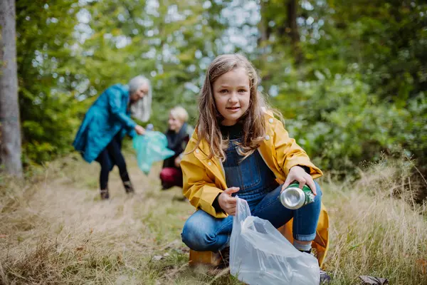 Kind sammelt in einem Wald Müll auf