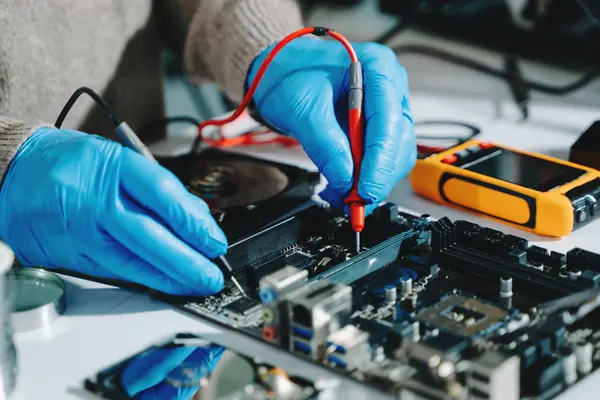 Eine Person repariert vor sich auf dem Tisch liegende Elektronik 