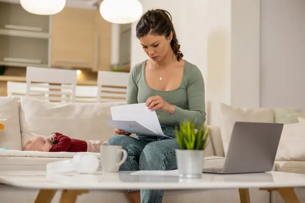 Eine Frau auf dem Sofa studiert eine Rechnung