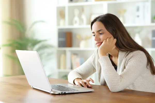 Junge Frau guckt enttäuscht auf Laptop-Bildschirm