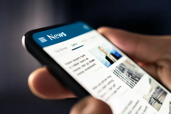 Mensch hält Handy mit News-App in der Hand