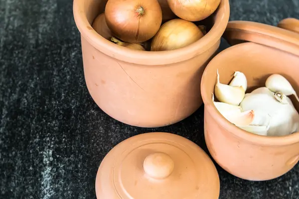 Zwei Römertöpfe mit Zwiebeln und Knoblauch drin