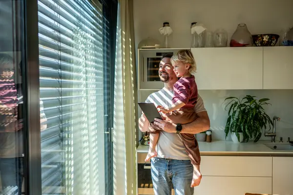 Mann bedient mit Kind auf dem Arm Außenrolläden