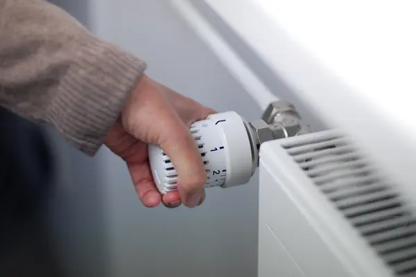 Hand an Thermostat einer Heizung 
