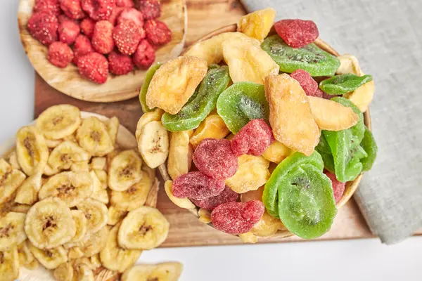 Verschiedene Teller mit gefriergetrocknetem Obst wie Erdbeeren, Bananen und Kiwi