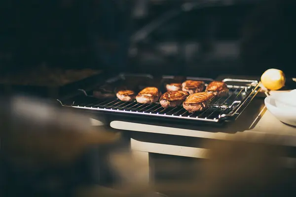 Von der Sonne beschienener Grill, auf dem gegrilltes Fleisch liegt