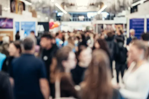 Volle Messehalle mit viele Ständen und Menschen