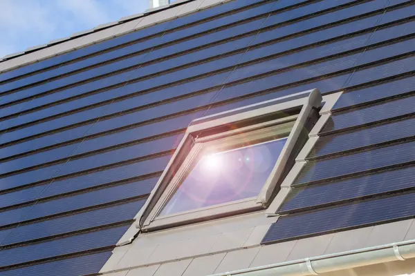 Solardachziegel umgeben ein Dachfenster, das das Sonnenlicht reflektiert.