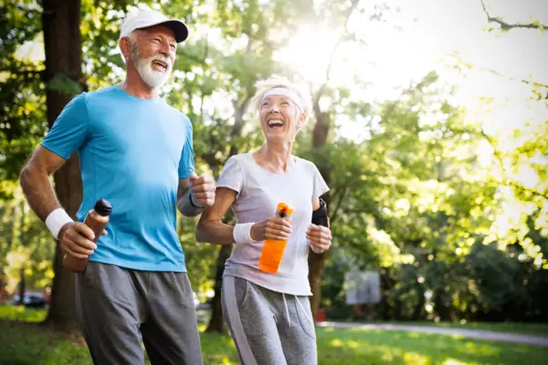 eine Seniorin und ein Senior bei einer leichten sportlichen Bewegung im Wald