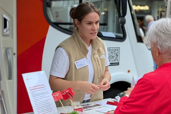 Mitarbeiterin der Verbraucherzentrale im Beratungsgespräch an einem Infostand.