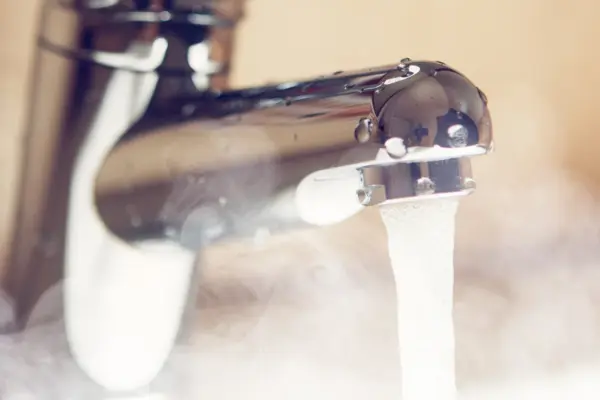 aus einem Wasserhahn fließt heißes, dampfendes Wasser