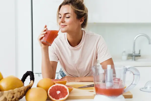 Eine Frau trinkt ein Glas Grapefruitsaft.