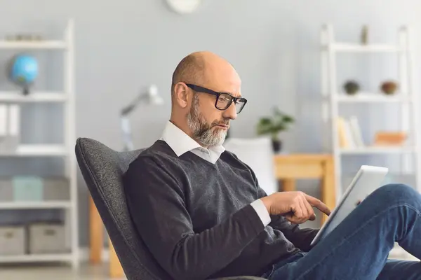 mann sitzt mit seinem Tablet auf einem Sessel