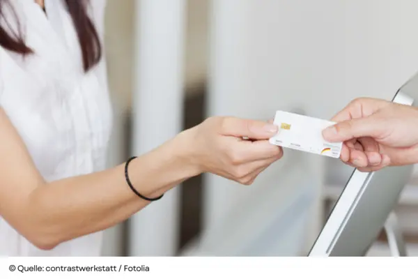 Übergabe einer Chipkarte (Krankenkassenkarte) am Praxisempfang.