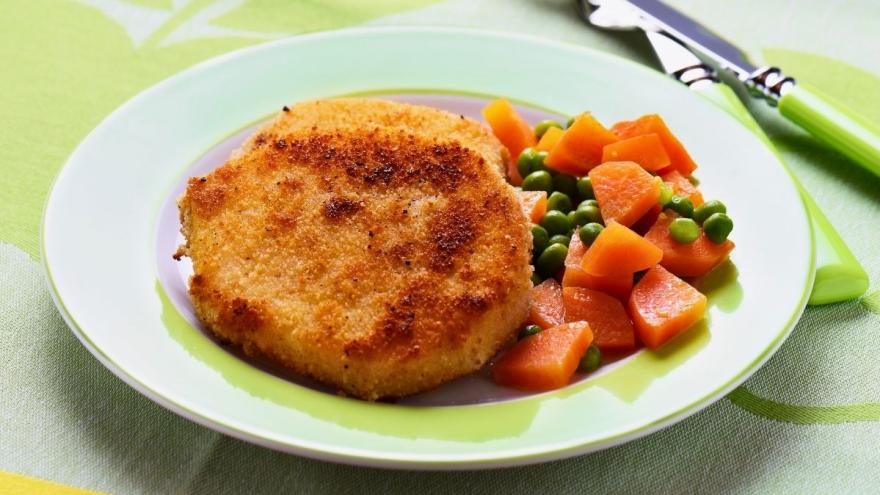 Sellerieschnitzel mit Erbsen und Möhren auf einem Teller.