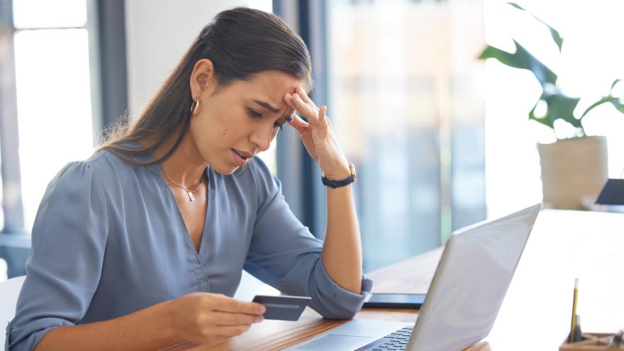 Schmuckbild: Frau mit besorgtem Gesichtsausdruck hält eine Kreditkarte in der Hand, während sie sich offensichtlich über ein finanzielles Problem oder einen Betrugsfall im Zusammenhang mit Online-Zahlungen oder Bankgeschäften ärgert.