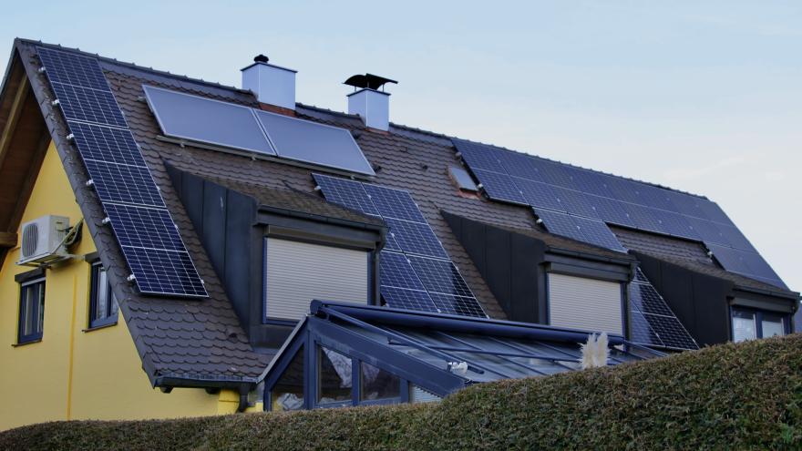 Hausdach mit Solaranlage: Photovoltaik-Module und Solarthermie-Kollektoren nebeneinander installiert.