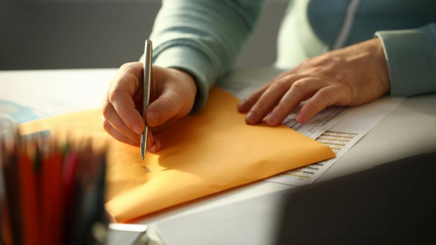 Briefe beschriften: Jemand schreibt eine Adresse auf einen gelben Briefumschlag