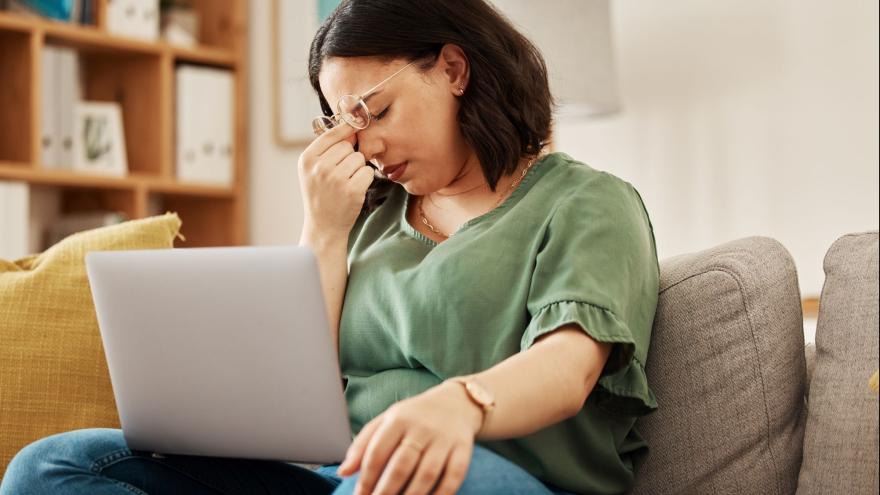 Frau auf dem Sofa mit Laptop auf dem Schoß mit frustriertem Gesichtsausdruck