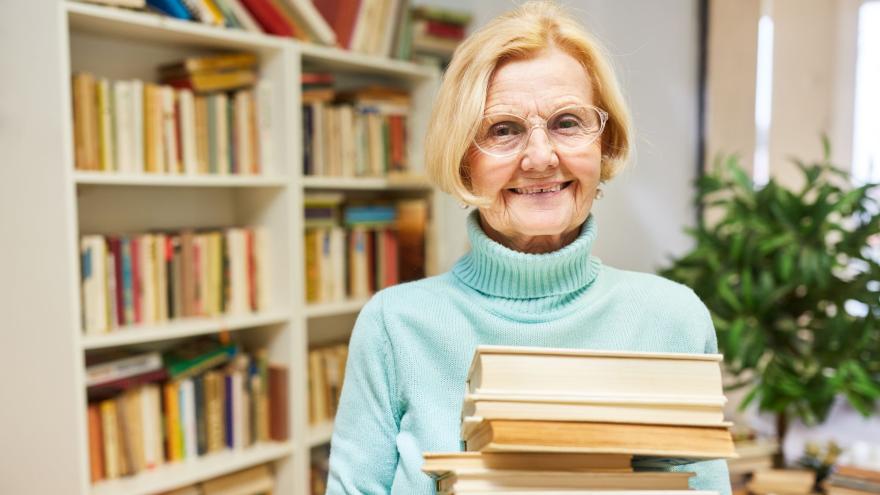 Rentnerin mit einem Stapel Bücher im Arm