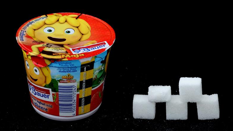 Joghurtbecher von Bauer und daneben eine Zuckerwürfel-Pyramide