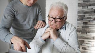 Schmuckbild: Älterer und jüngerer Mann schauen gemeinsam auf Laptop