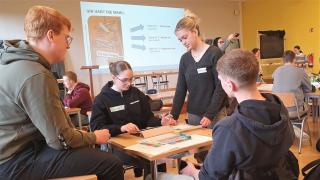 Vier junge Menschen arbeiten gemeinsam an einem Gruppentisch in einem Klassenraum.