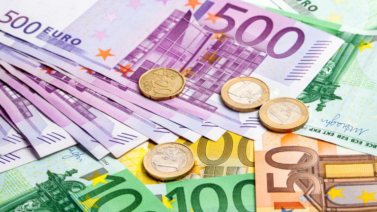Große Euro-Scheine und Münzen liegen aufeinander.