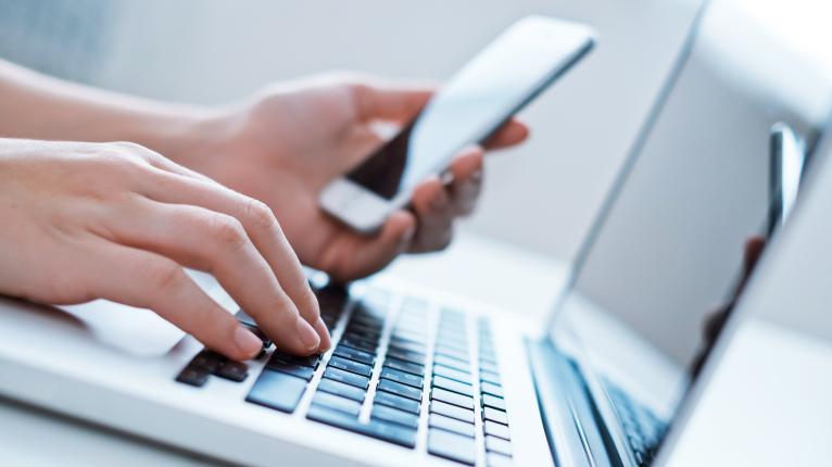 Nahaufnahme von jemandem, der Laptop und Smartphone nutzt